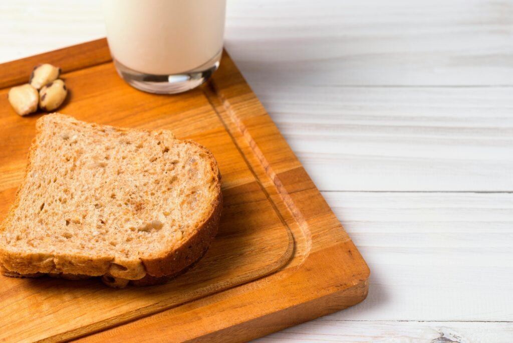 A close-up of a slice of whole wheat bread with a glass of milk, perfect for a healthy breakfast.